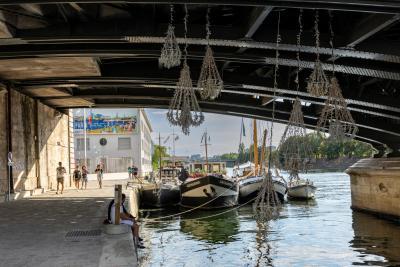 La Seine Artistique "Sens dessus dessous", sous un pont à Paris, des bateaux et une oeuvre culturelle. En arrière plan, une publicité HAROPA PORT. - Agrandir l'image 1 sur 3, fenêtre modale