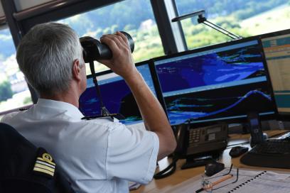Officier de port de la vigie d'Honfleur de la capitainerie de HAROPA PORT Rouen regardant la navigation en Seine à l'aide de jumelle. Il est derrière son ordinateur. - Agrandir l'image, fenêtre modale