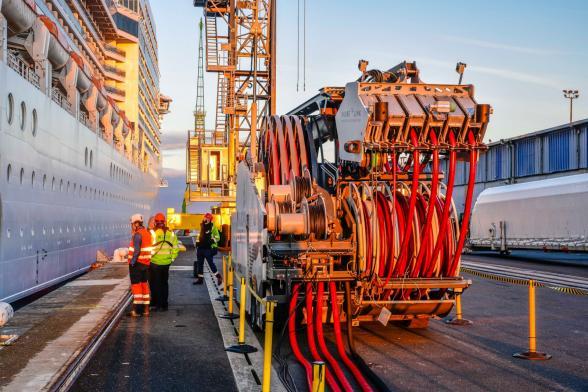Groupe de personnes opérant le branchement électrique du navire MSC Poesia au quai Pierre Callet du Havre grâce à l'utilisation d'un véhicule équipé de bras articulés et de câbles. - Agrandir l'image, fenêtre modale