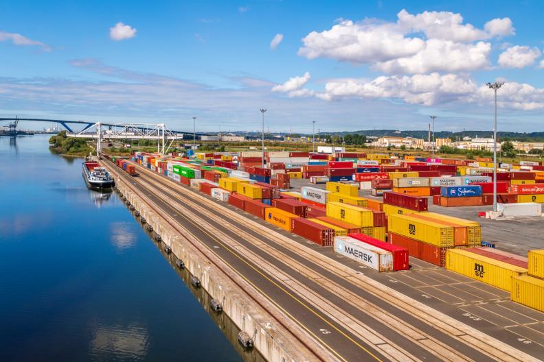 Le terminal multimodal du Havre avec une barge accosé et un train en action. Des conteneurs rouges et jaunes à droite. - Enlarge image, modal window